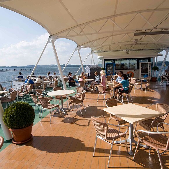 Das oberste Deck der MS Brombachsee. An Stühlen und Tischen sitzen Gäste unter einem großen Sonnensegel.