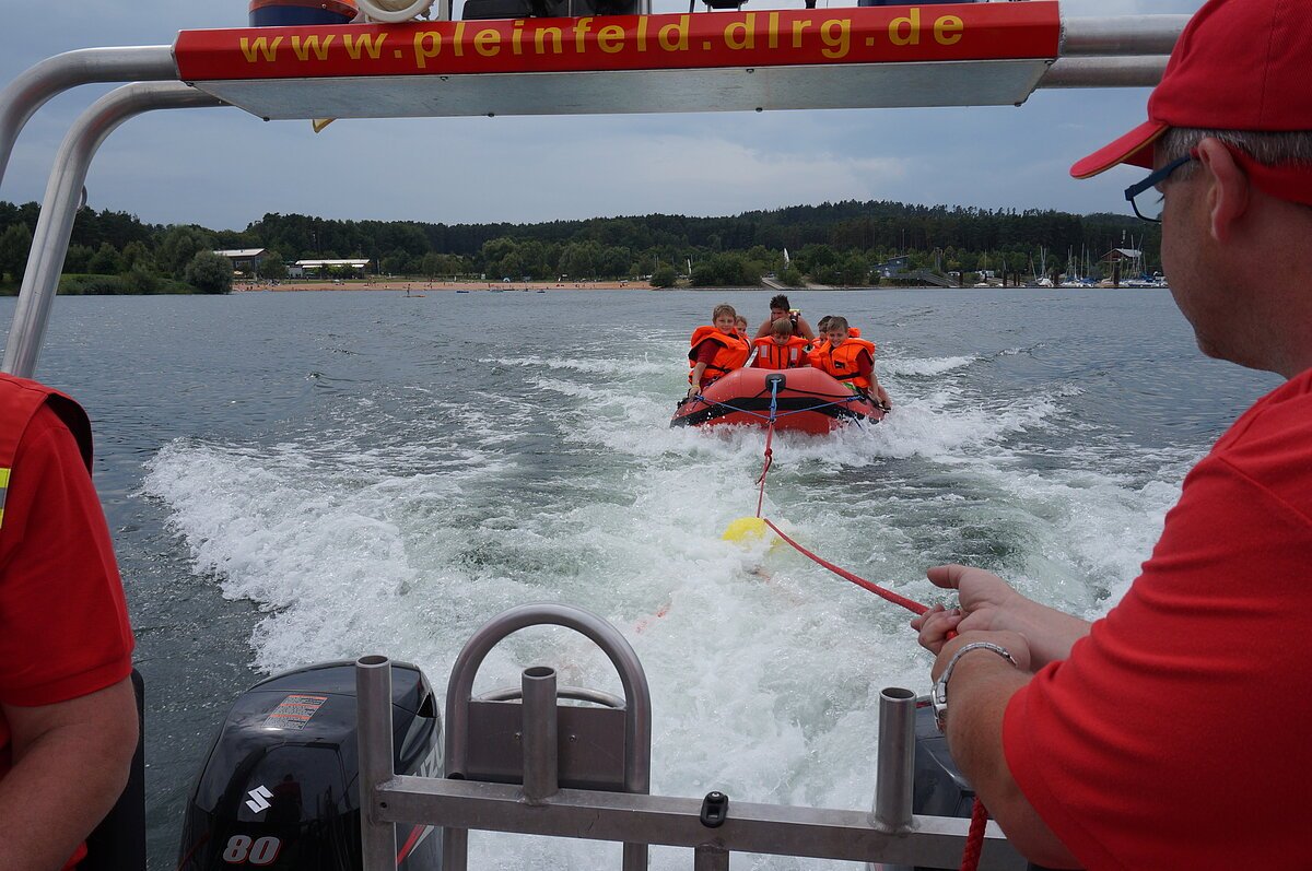 Die DLRG schleppt ein Schlauchboot mit Jugendlichen ab. (Beim Sommerferienprogramm)